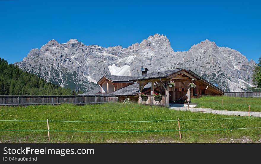 Typical chalets in the Italian Alps, with flowers, wooden facade and timber and great fence and path in the front part