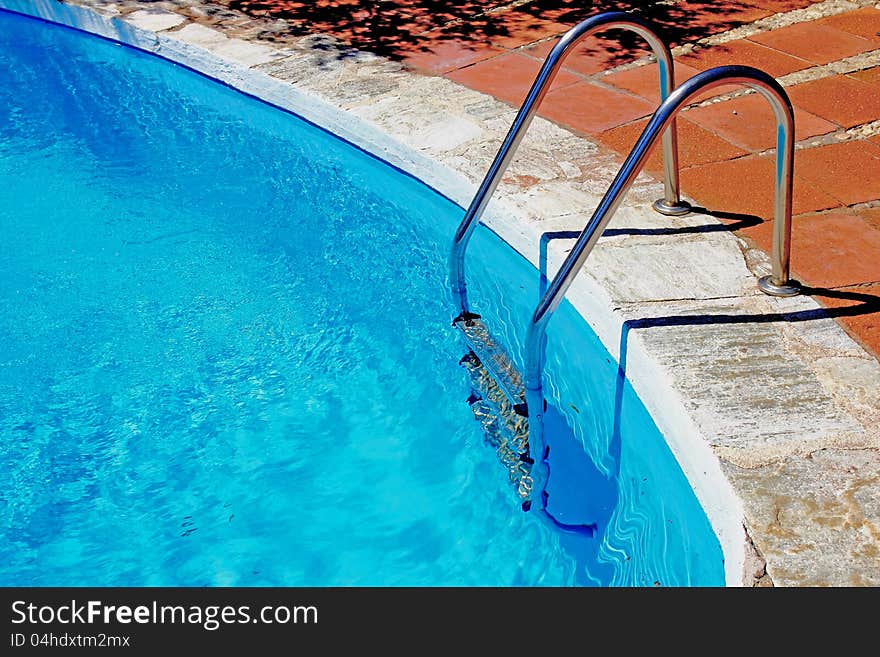 Ladder to swimming pool with blue water.