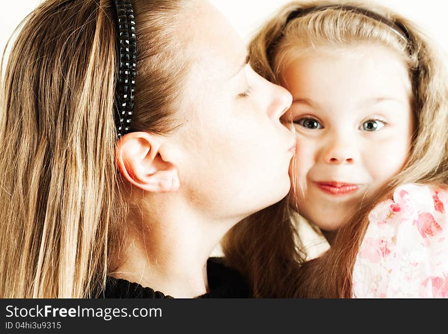 The little girl tenderly kisses his mother with his eyes closed. The little girl tenderly kisses his mother with his eyes closed