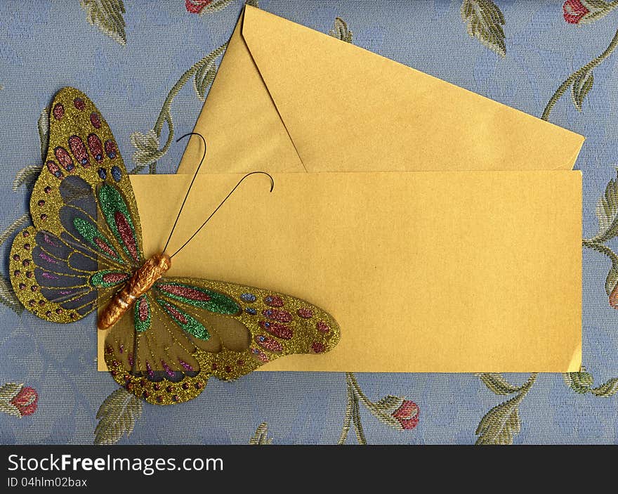 Beautiful butterfly made in fabric on texture background with golden paper sheet and envelope. Beautiful butterfly made in fabric on texture background with golden paper sheet and envelope