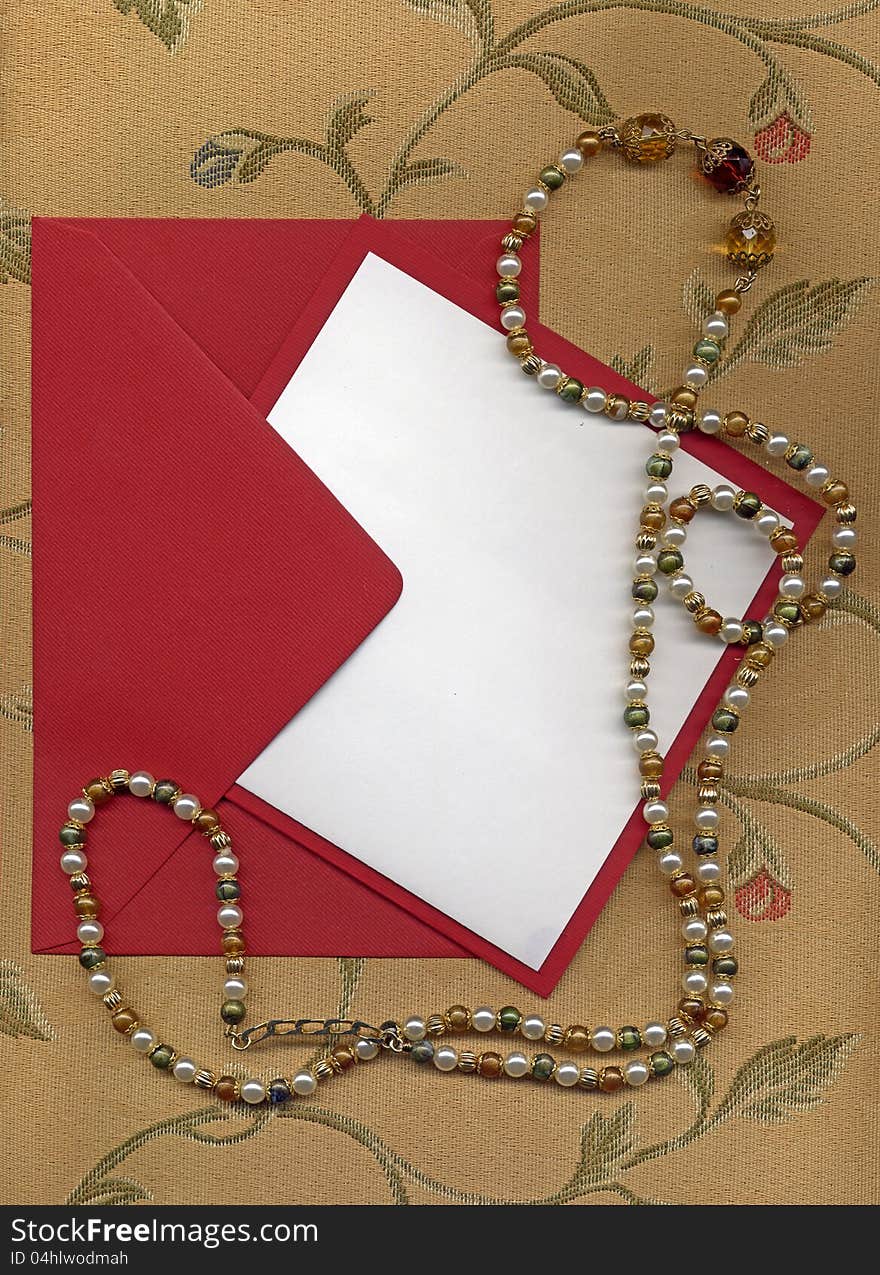 Paper sheet and red envelope on textile with necklace. Paper sheet and red envelope on textile with necklace