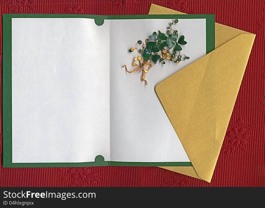 Paper sheet and golden envelope on textile with handmade shamrocks. Paper sheet and golden envelope on textile with handmade shamrocks