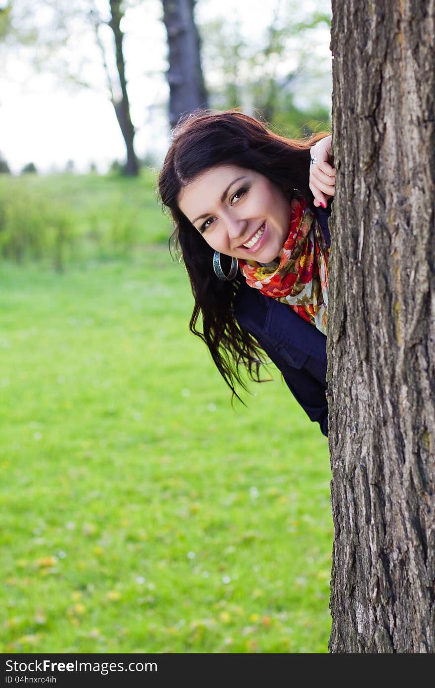 Beautiful young girl near tree in the park