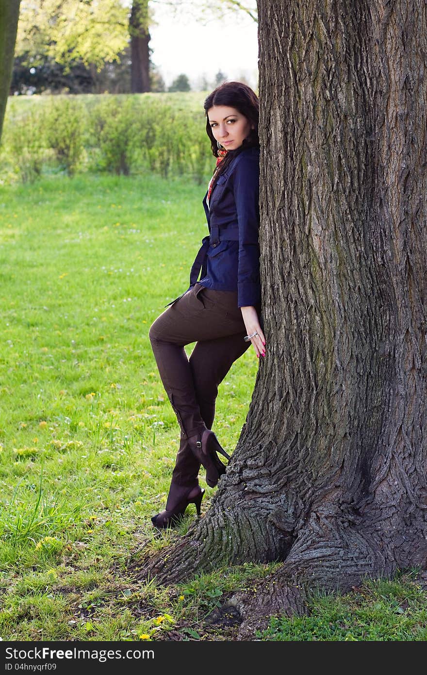 Beautiful young girl near tree in the park