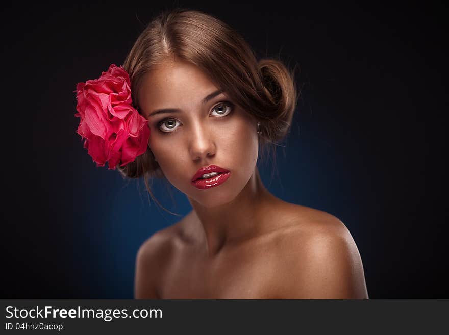 Beauty face of the young woman with flower. Girl on dark blue background