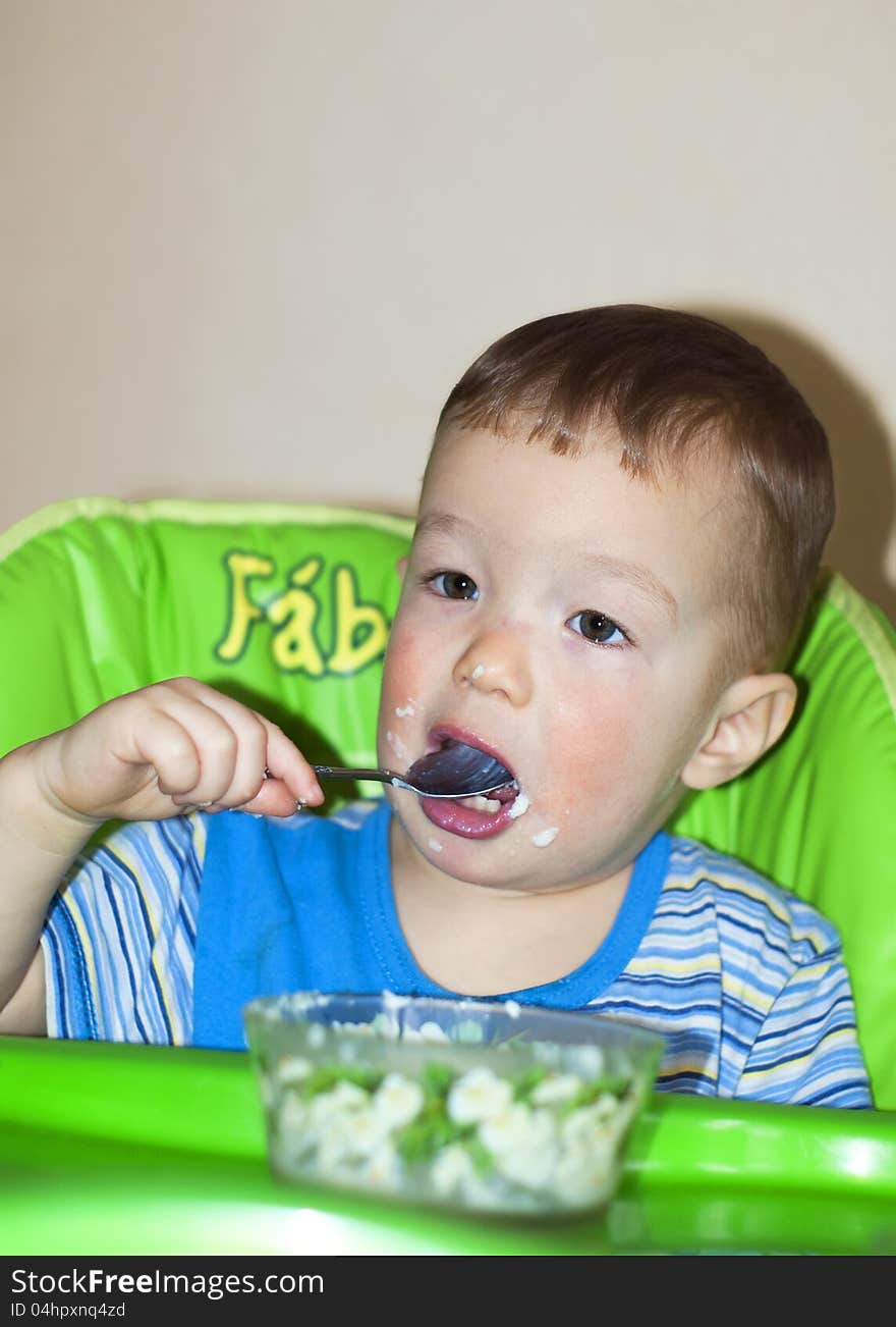 Hungry small boy eating porrige himself. Hungry small boy eating porrige himself