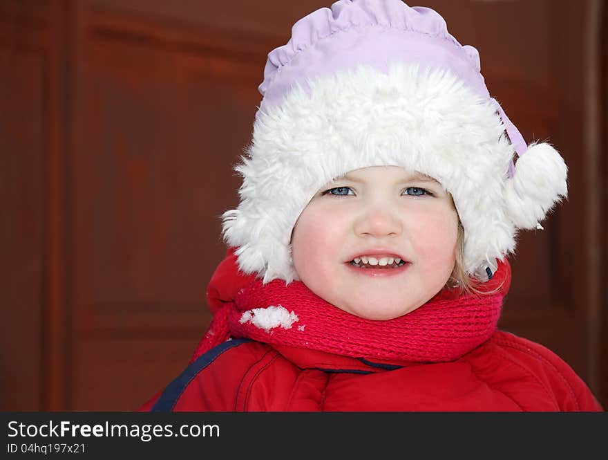 Cute little girl wearing warm clothing stands and looks at camera. Cute little girl wearing warm clothing stands and looks at camera