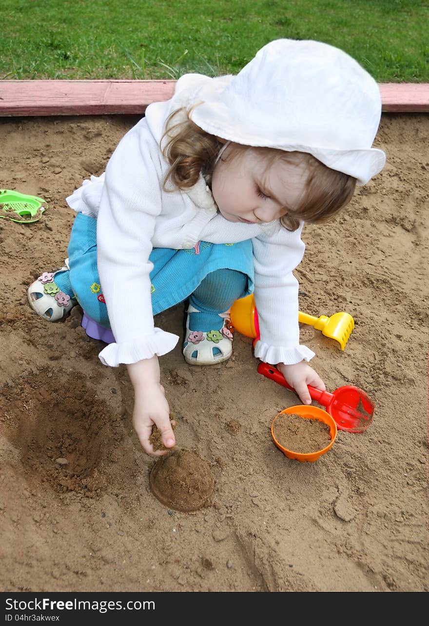 Little cute girl plays in sandbox