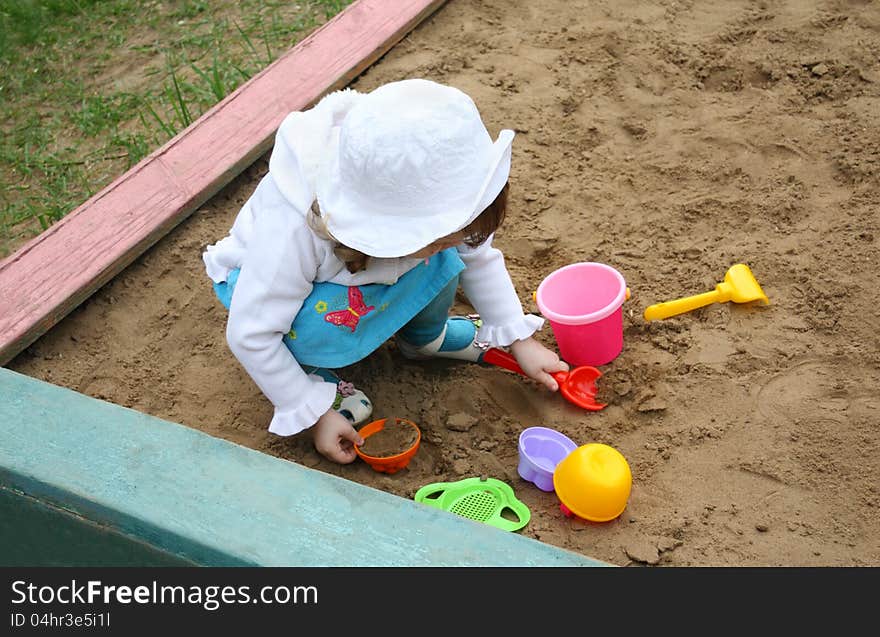 Llittle girl plays in sandbox at playground