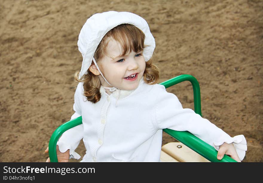 Happy cute girl rides on small carousel