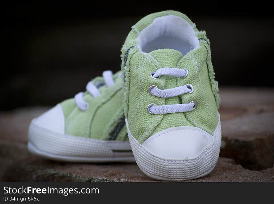 Green baby sneaker shoe on black background.