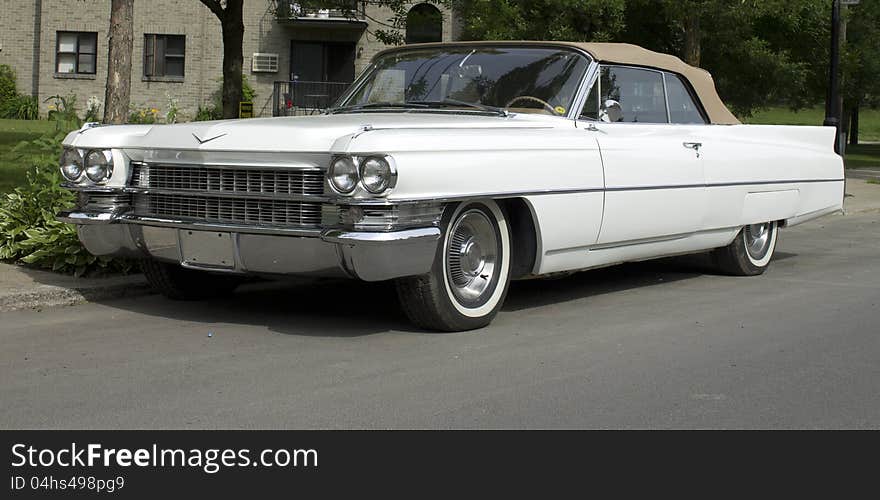 A white 60's classic convertible american car with white wall tires and beige leather top. A white 60's classic convertible american car with white wall tires and beige leather top