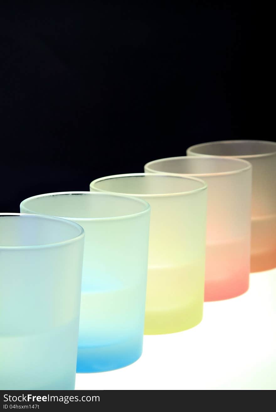 Colorful glasses on bar table . Vertical shot against black background. Colorful glasses on bar table . Vertical shot against black background