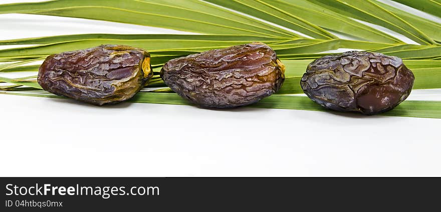 Ripe dates and green palm's leaves isolated on white background. Ripe dates and green palm's leaves isolated on white background