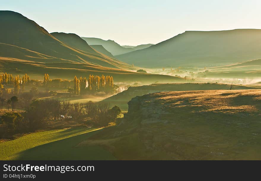 Early sun casts a golden light over the valley in the Drakensberg mountains. Early sun casts a golden light over the valley in the Drakensberg mountains