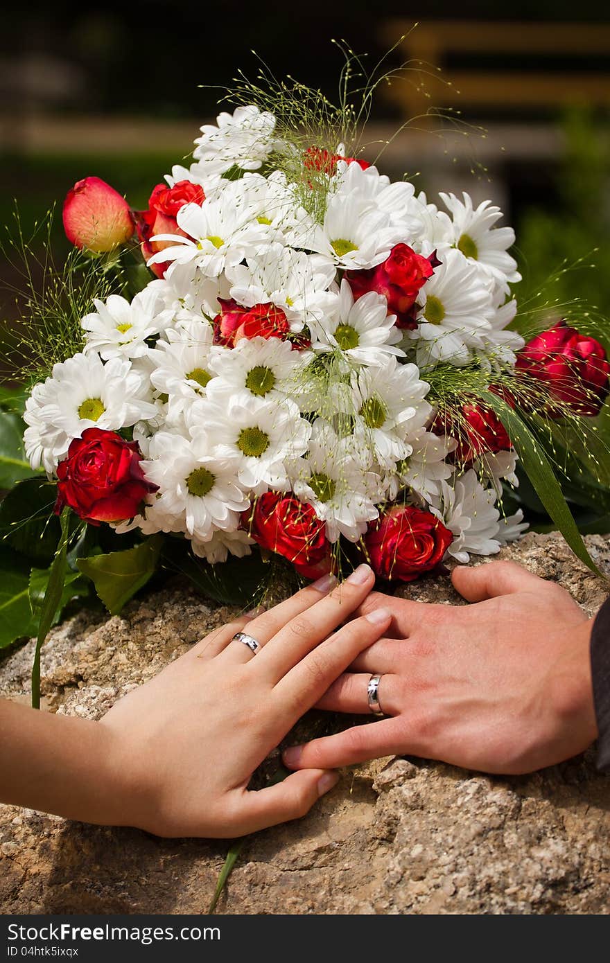 Wedding rings on their hands with flowers.