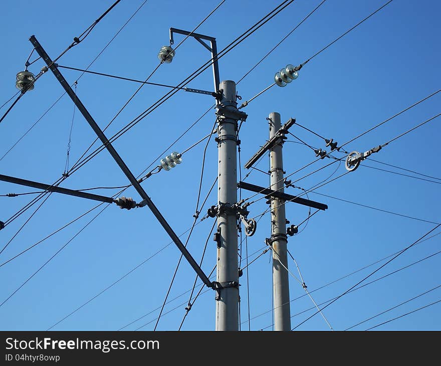 Electrical post with power line cables against blue sky.