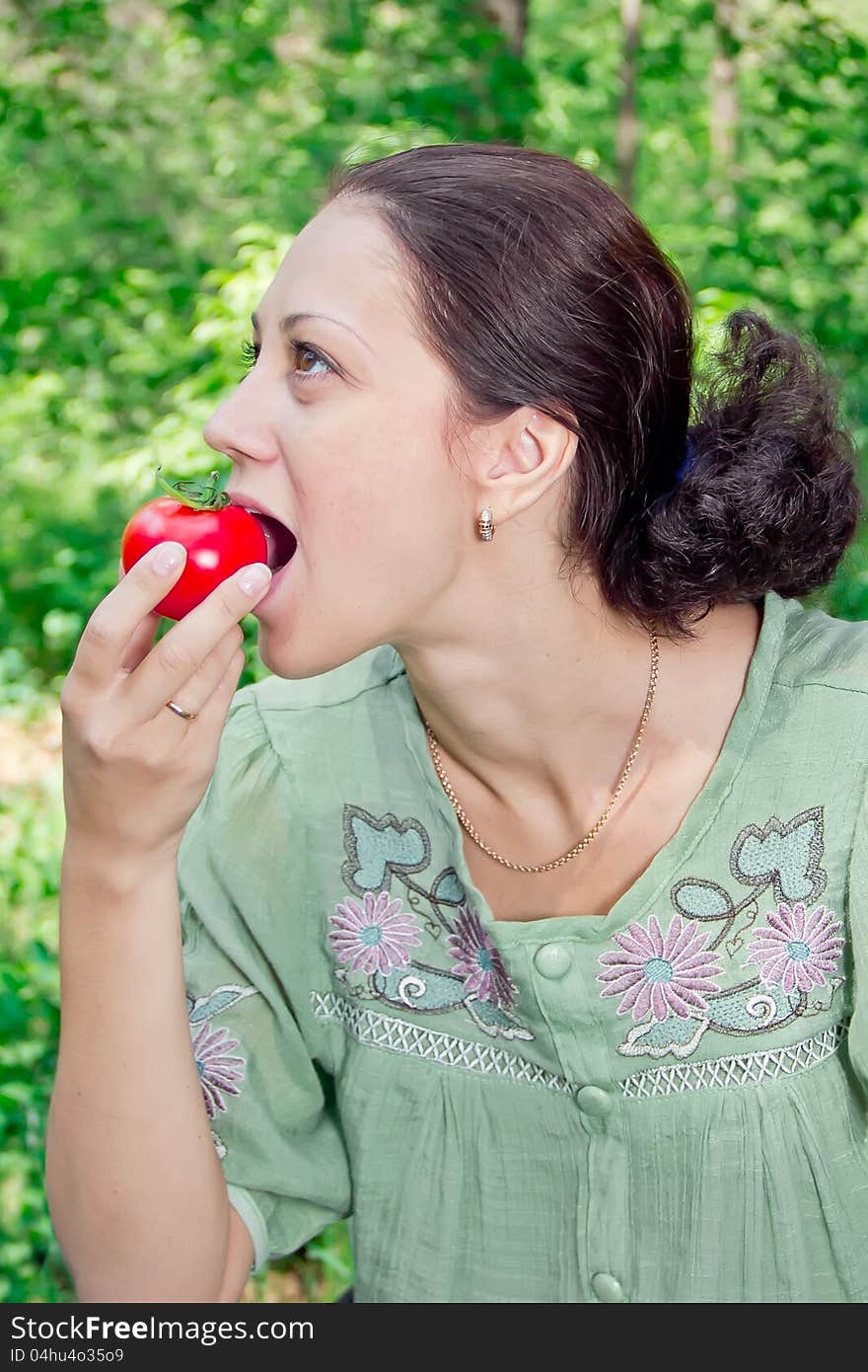 A young woman eating tomato. A young woman eating tomato