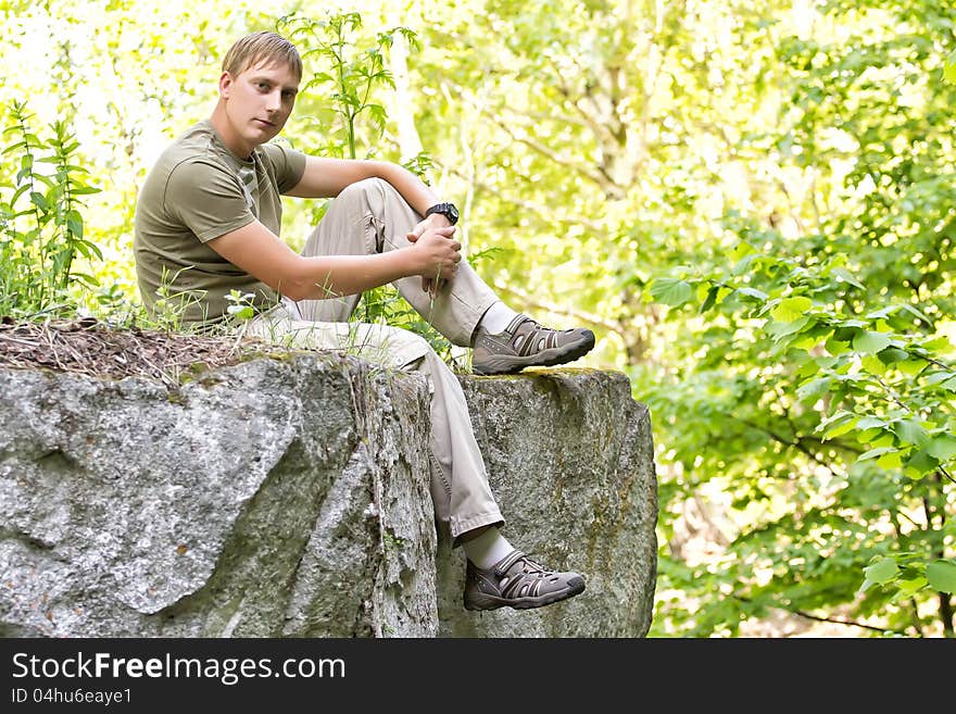 He young man sits on the edge of a cliff. He young man sits on the edge of a cliff