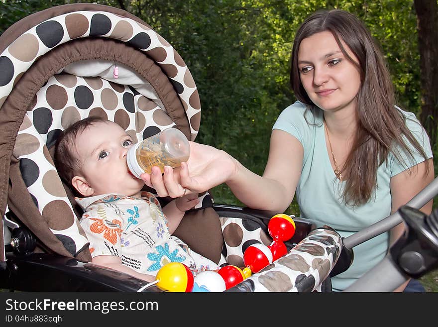 Mother feeding newborn son with feeding bottle