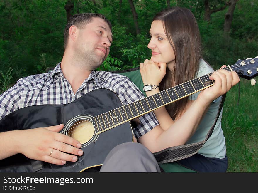 Romantic young couple embracing playing guitar