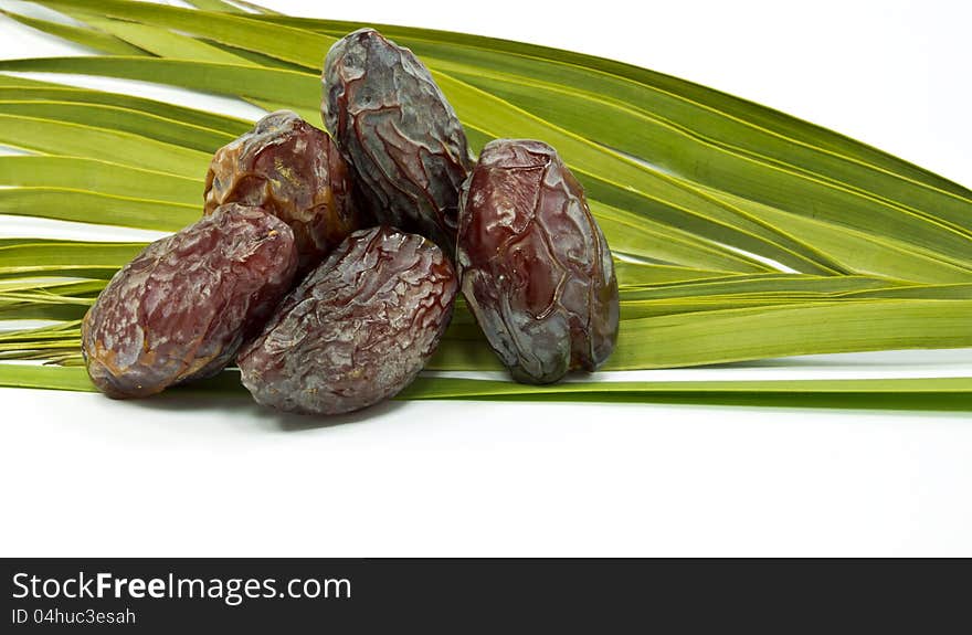 Ripe dates and palm leaves on white background