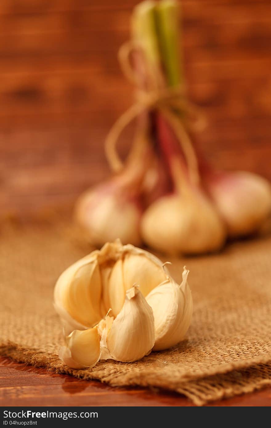 Summer garlic on burlap in rustic background