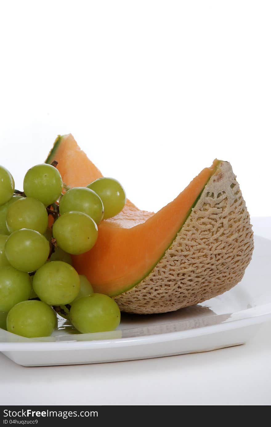 Cantaloupe and green grapes on white plate