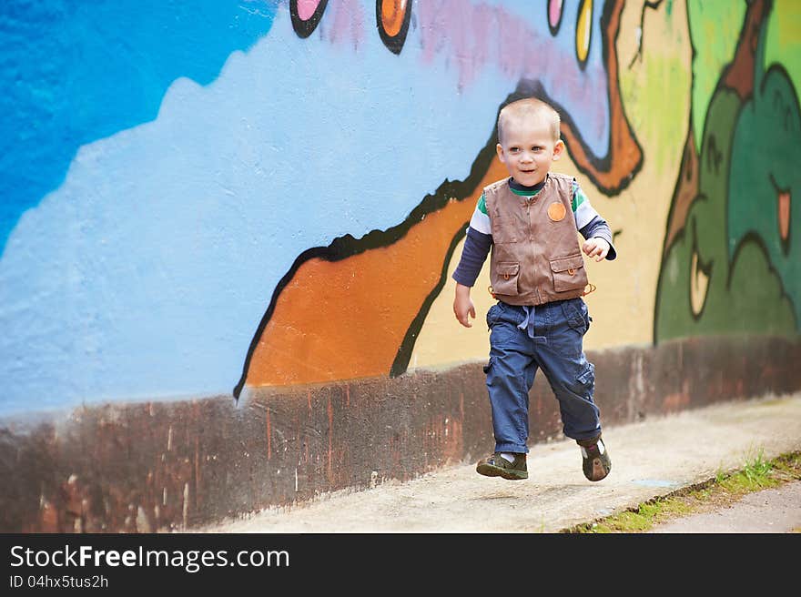 Cheerful boy running on a colored background. Cheerful boy running on a colored background