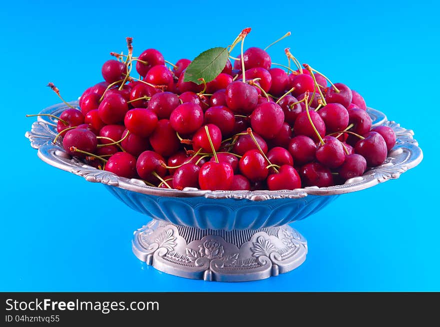 Cherry poured into a silver vase photographed against a blue background. Cherry poured into a silver vase photographed against a blue background