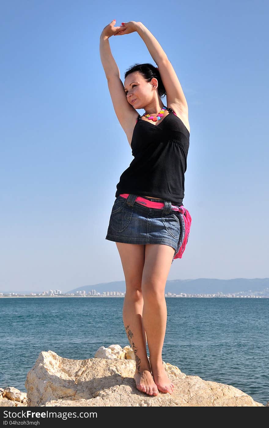 Young girl dancing barefoot on a rock on the shore of the Mediterranean Sea. Young girl dancing barefoot on a rock on the shore of the Mediterranean Sea