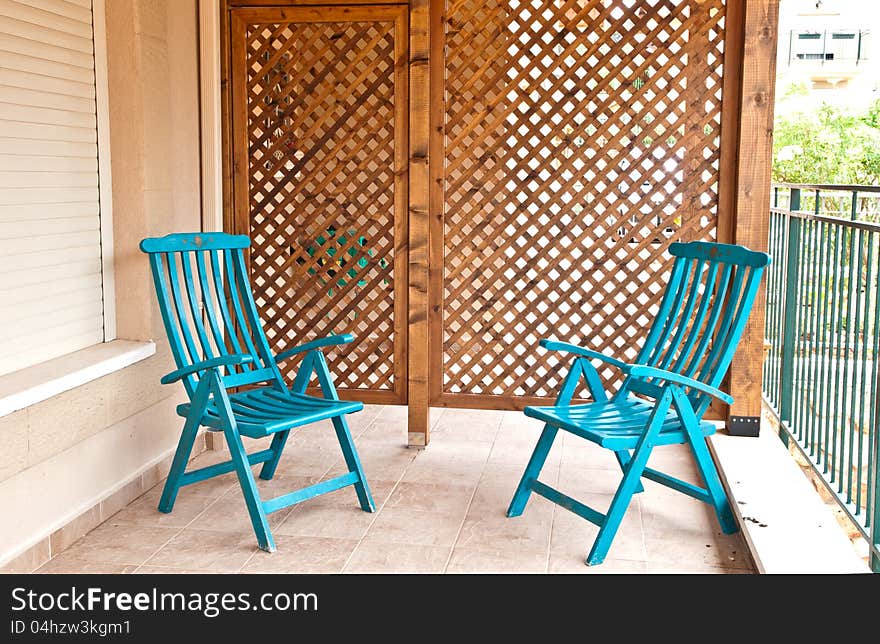 Fragment of a village house with a wooden lattice wall and two wooden chairs. Fragment of a village house with a wooden lattice wall and two wooden chairs