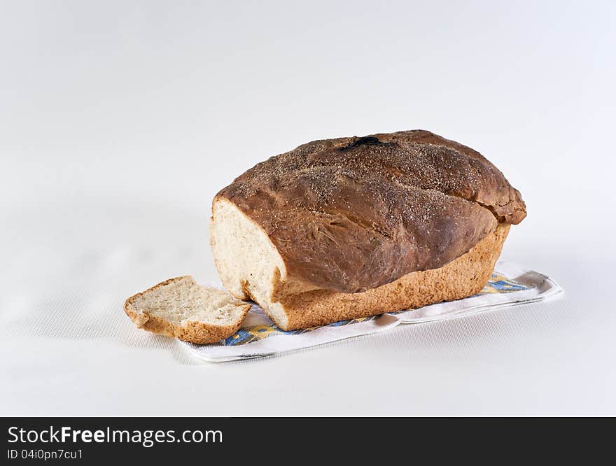 Loaf and slice of white wheat bread on the table-napkin. Loaf and slice of white wheat bread on the table-napkin