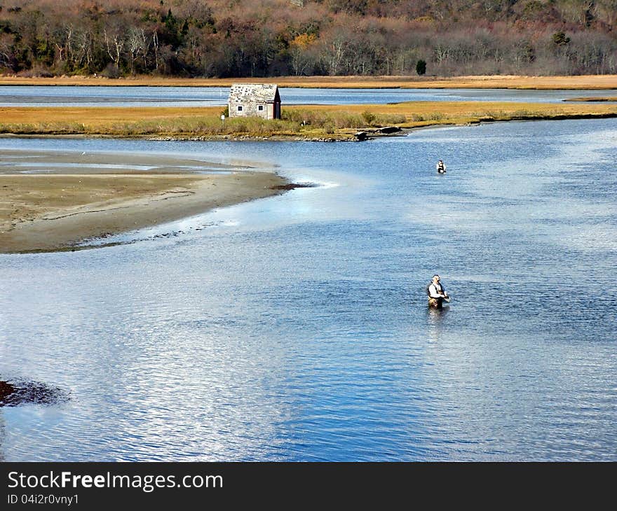 Nice summer day at the river with men flyfishing at low tide and a fishing hut to sleep in. Nice summer day at the river with men flyfishing at low tide and a fishing hut to sleep in.