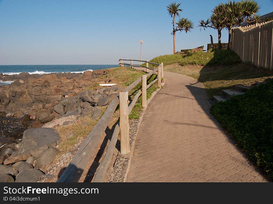 A pathway with wooden rail, running along the shore at Ballito, KwaZulu-Natal North Coast, South Africa. A pathway with wooden rail, running along the shore at Ballito, KwaZulu-Natal North Coast, South Africa.