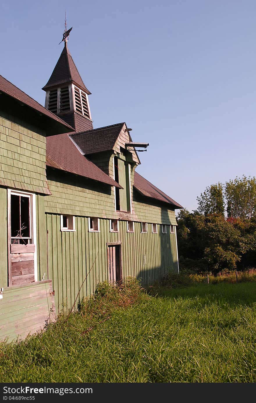 A green slatted barn with a slatted cupola and weather vane on top. A green slatted barn with a slatted cupola and weather vane on top.