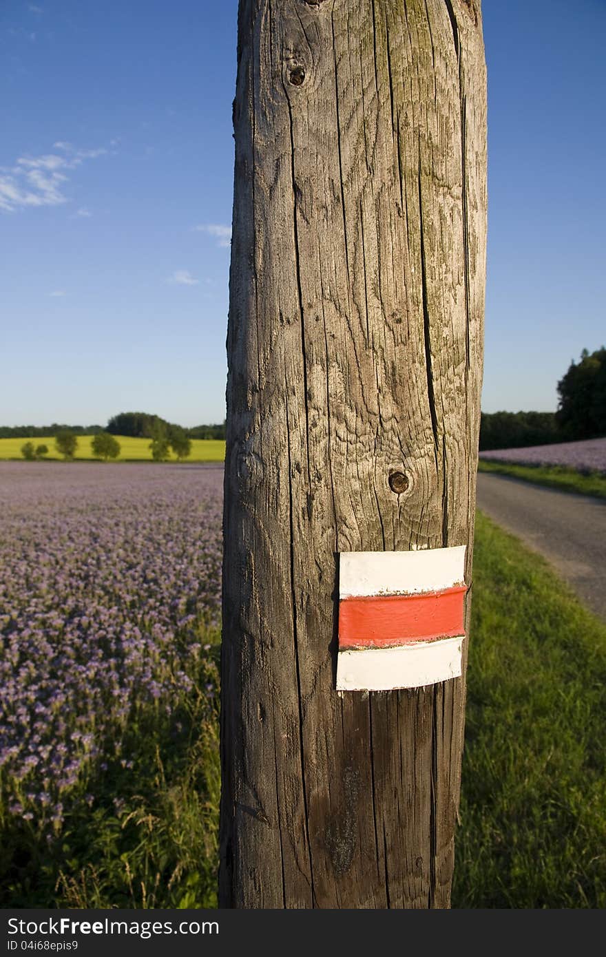 Red and white sign on a wooden pole, landmark in the landscape for tourists. Red and white sign on a wooden pole, landmark in the landscape for tourists