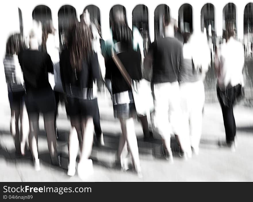 A group of people standing in the city looking at something else. A group of people standing in the city looking at something else.