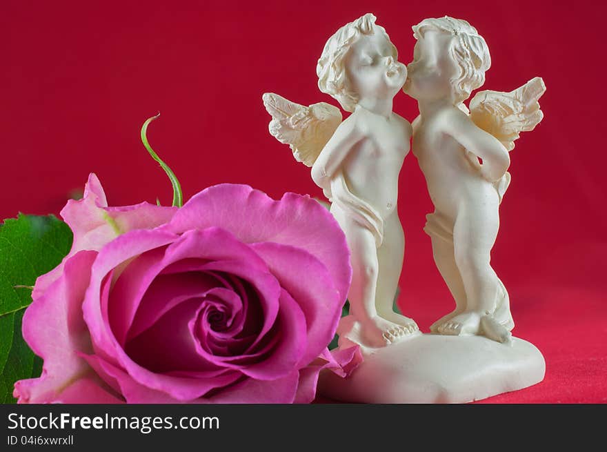 Angels kissing with pink rose on red background. Angels kissing with pink rose on red background