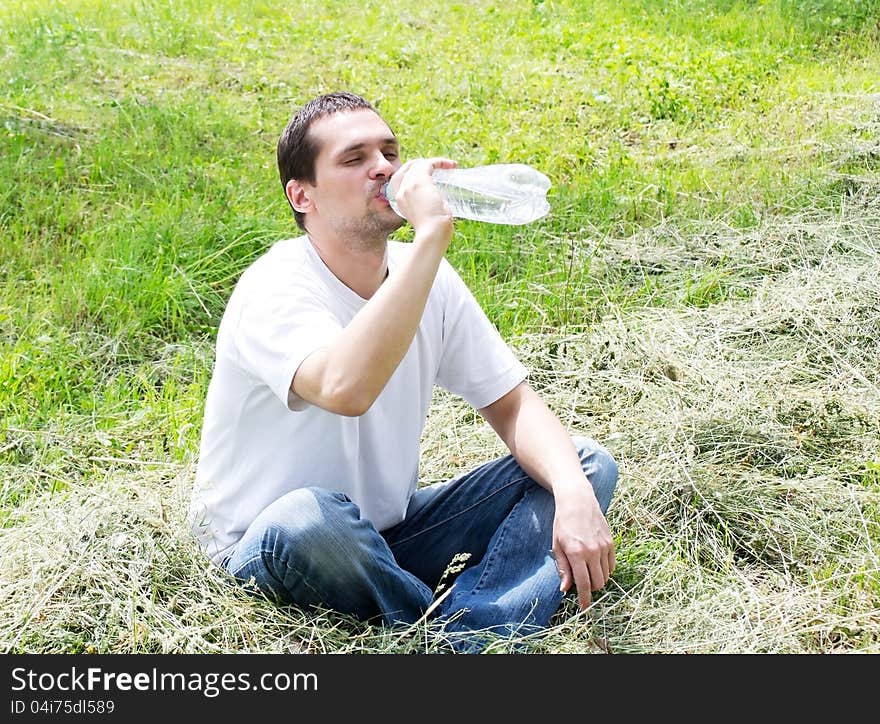 Young man eagerly drinking water from plastic bottles