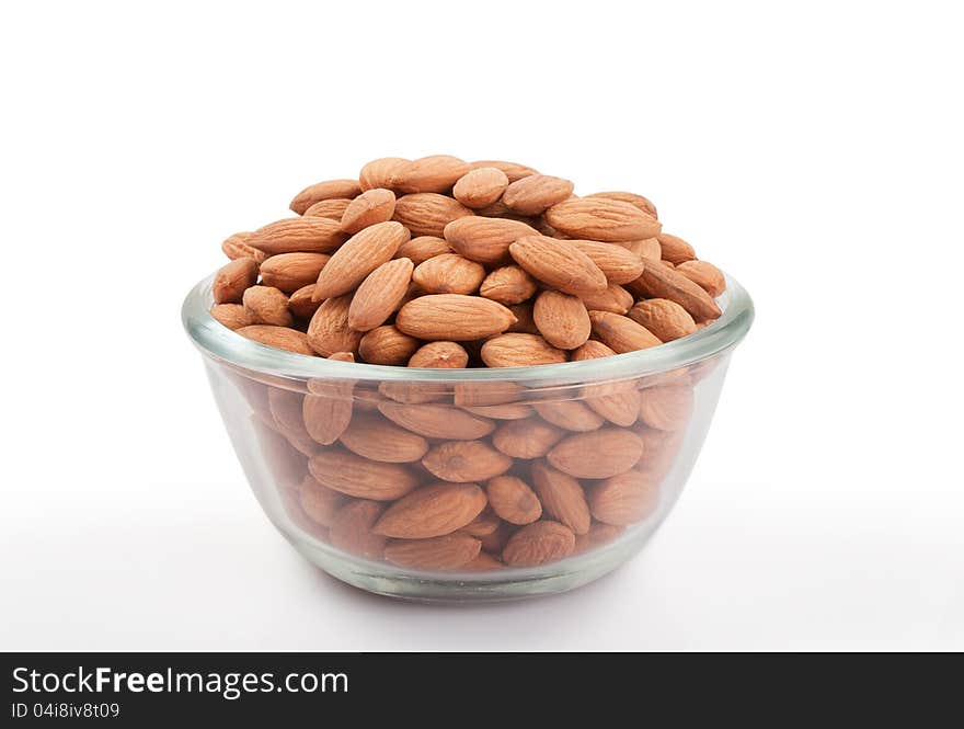 Pile of  almonds in transparent glass small bowl  over white background