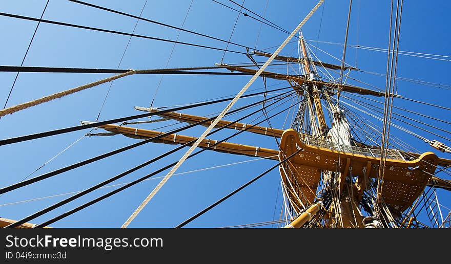 Masts and rigging on the old ship at the sky background. Vintage sailing ship mast and ropes on ancient nautical vessel.