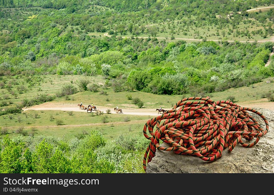 Climbing rope on the peak of the mount. Climber rope on the high rock. Mountain landscape with alpine rope at the edge of cliff. Active leisure in nature - rock climbing and horseback riding. Climbing rope on the peak of the mount. Climber rope on the high rock. Mountain landscape with alpine rope at the edge of cliff. Active leisure in nature - rock climbing and horseback riding.