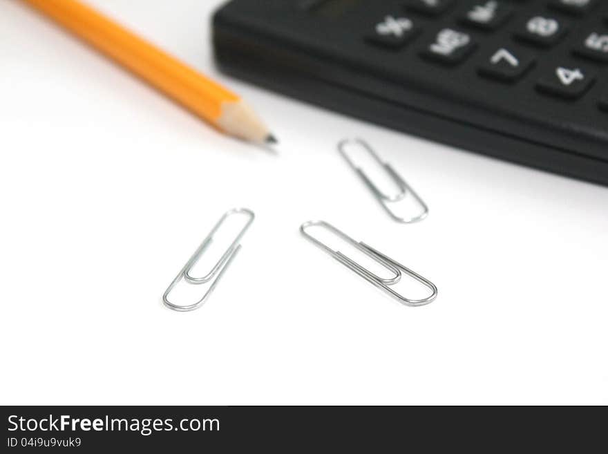 Calculator, pencil and paper clips over white piece of paper. Calculator, pencil and paper clips over white piece of paper