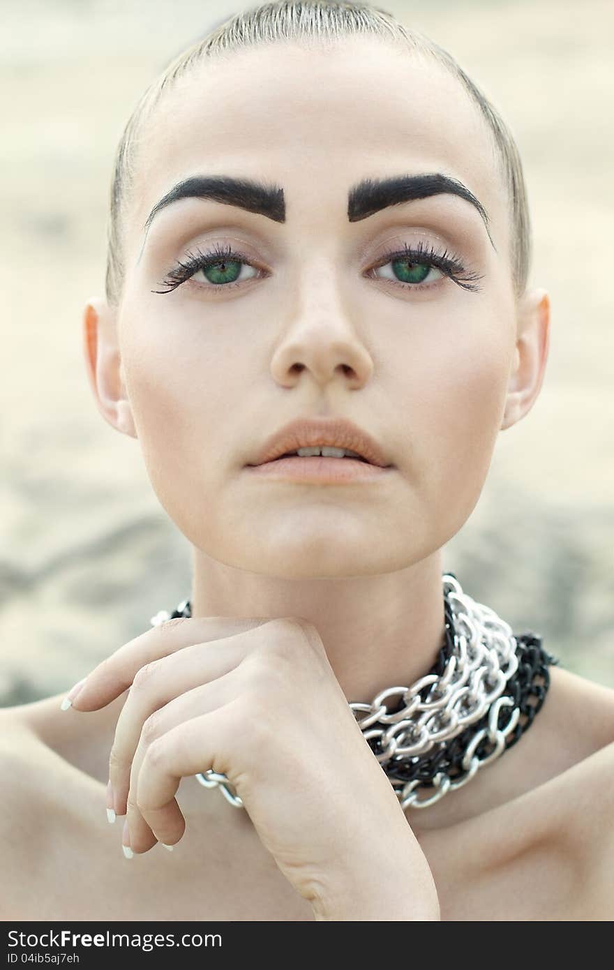 Fashion portrait of beautiful woman with chained neck posing on lightfull background