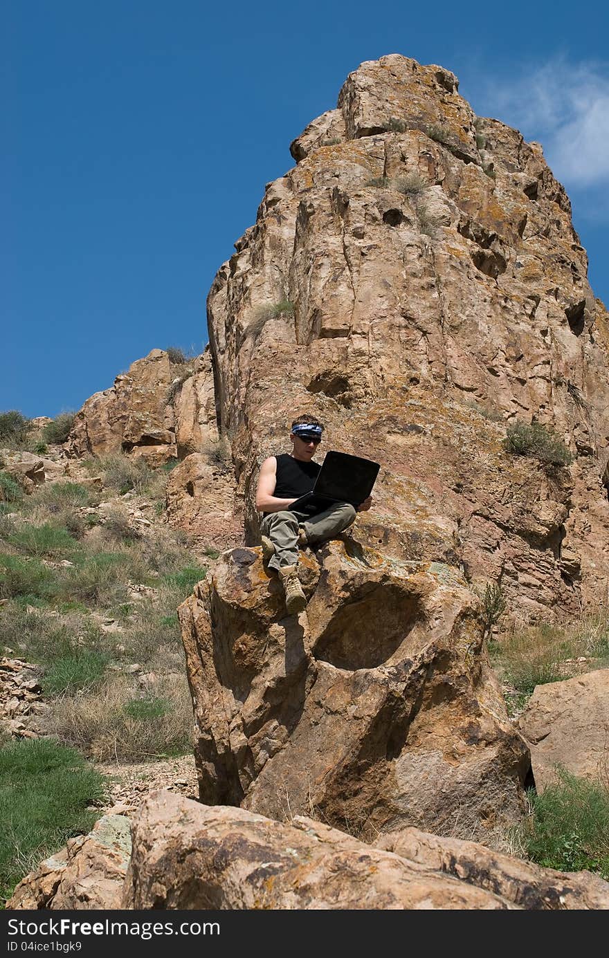 The man with the laptop sits in beautiful mountain district