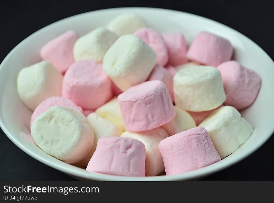 A bowl of pink and white marshmallows.