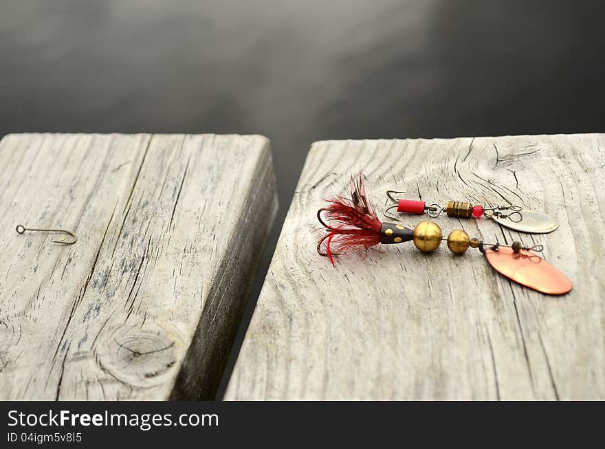 Fishing bait,wobbler on a bridge by the lake. And a hook on the side.