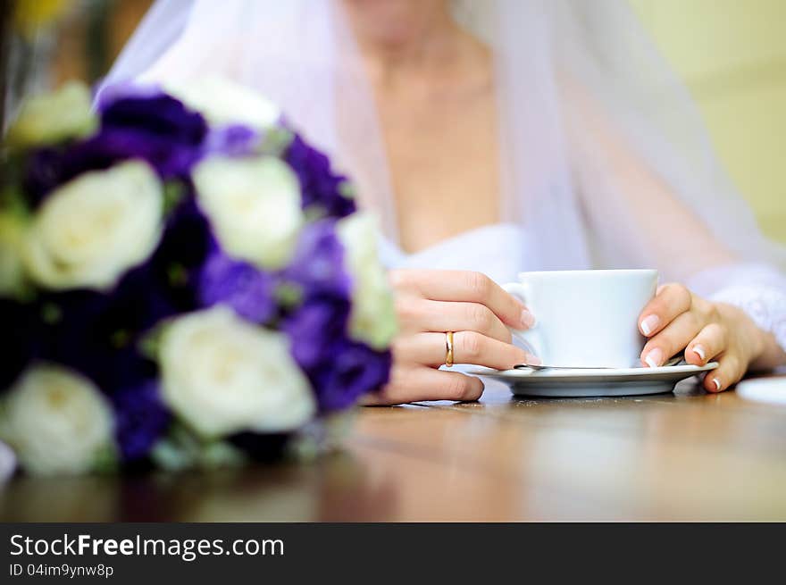 Bride holding coffee cup. Blur bride on a background.