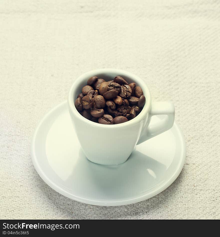 Coffee beans in a cup on white fabric